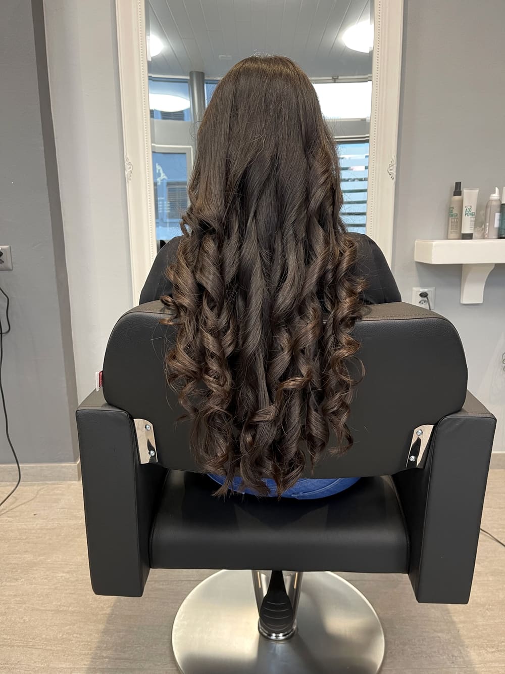 Lange dunkle Haare mit grossen, glänzenden Locken, von hinten fotografiert